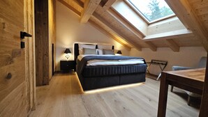A bedroom with a skylight, a bed, bedside tables, and a desk.
