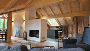 A spacious living room with a fireplace, wooden beams, and a skylight.