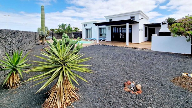 A modern house with a pool, a stone wall, and cacti. - Anna Holiday Home, private heated pool (Montaña Roja)