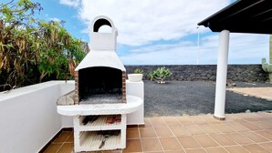 A stone oven on a tiled patio with a view of a lava field. - Anna Holiday Home, private heated pool (Montaña Roja)