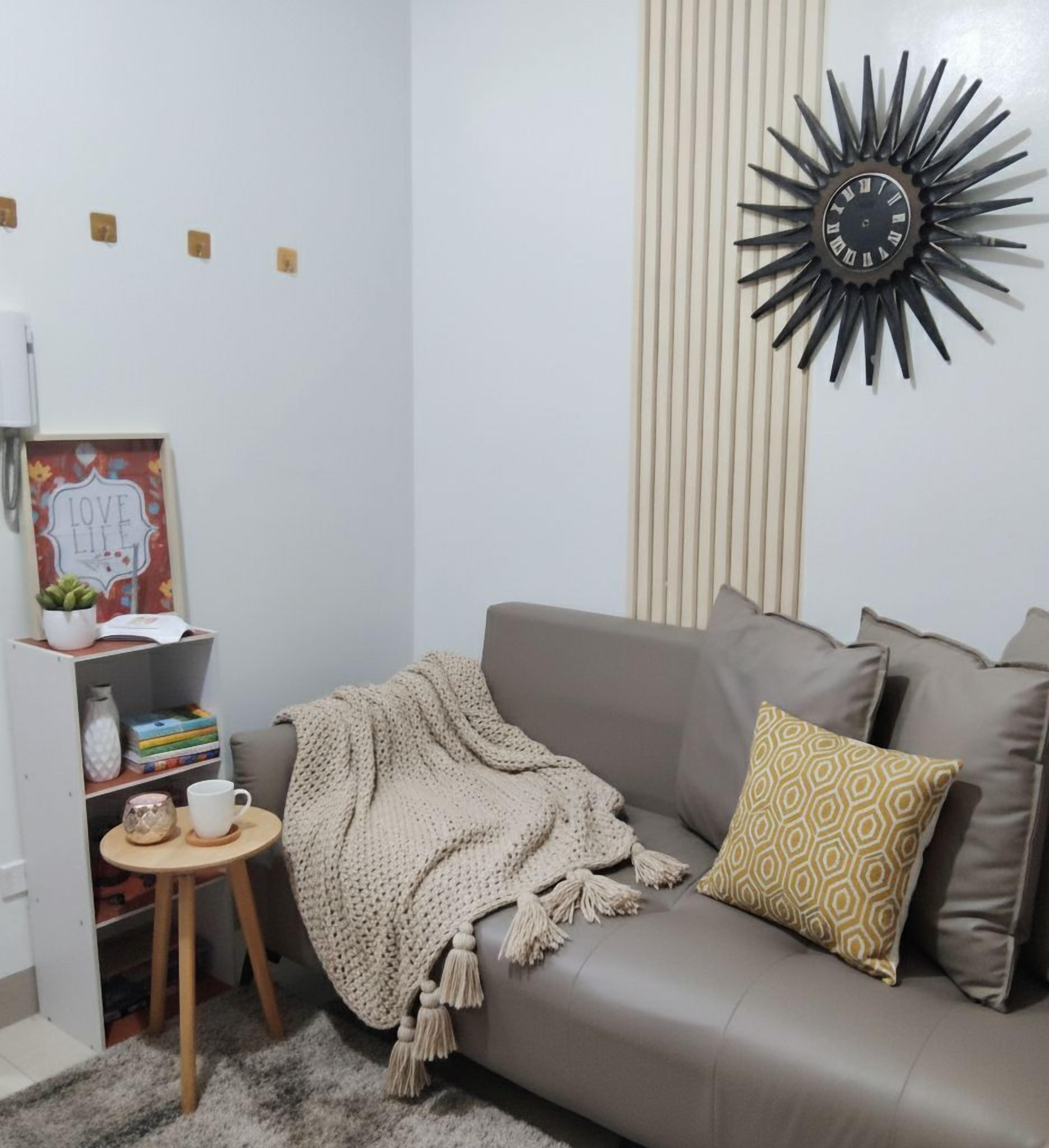 A living room with a sofa, a decorative wall clock, a small side table, and a bookshelf.