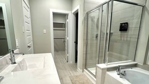 A modern bathroom with a large white sink, a bathtub, and a glass shower enclosure. - Master Bedroom with Private Bathroom (Houston)