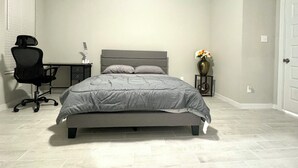 A bedroom with a bed, a desk, a chair, and a vase with flowers. - Master Bedroom with Private Bathroom (Houston)