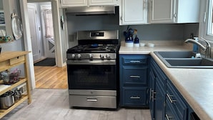 A modern kitchen with white cabinets, a stainless steel stove, and a sink. - Perfect 3+ Bedroom House for Rent-Sturgis Rally (Rapid City)
