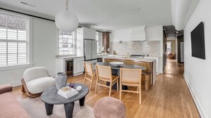 Una cucina moderna con mobili bianchi, un'isola centrale e sedie in legno.