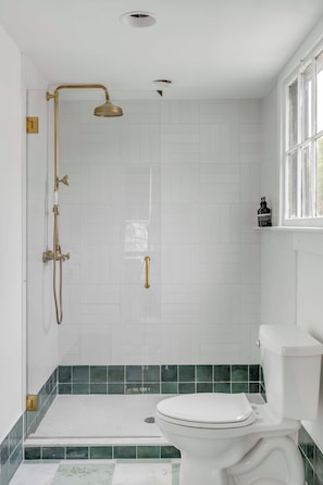 Une salle de bain avec une douche, des toilettes et une fenêtre.