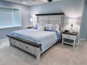 A bedroom with a bed, nightstands, a window with blinds, and a ceiling fan. - The Park House  A 5 Bedroom Retreat w/Game Room & (Huntington)
