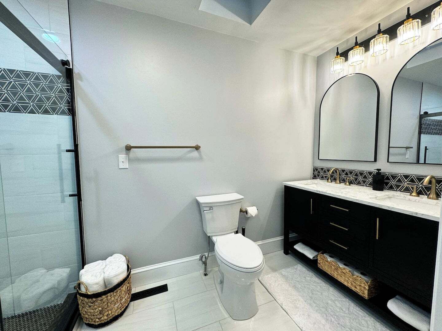 Een moderne badkamer met een douchecabine van glas, een toilet, een wastafel met spiegel en een handdoekrek.