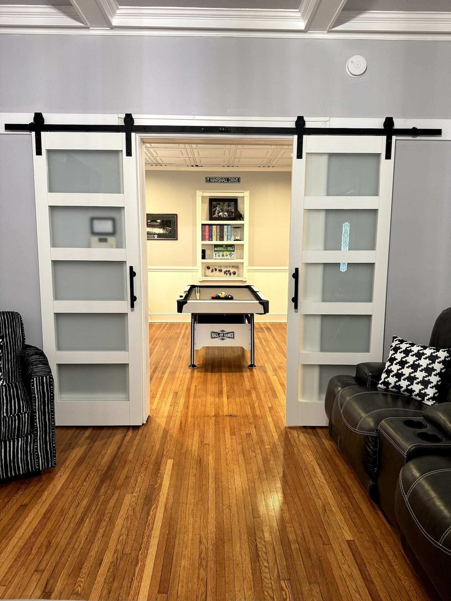 Ein Zimmer mit Holzboden, einem Kicker, einem Sofa und einer Couch mit gemustertem Kissen.