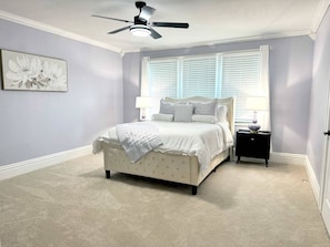 A bedroom with a bed, a nightstand, a ceiling fan, and a window with blinds. - The Park House  A 5 Bedroom Retreat w/Game Room & (Huntington)