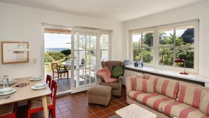 Amplia sala de estar con mesa de comedor, sillas, sofá y ventana con vistas a un jardín.