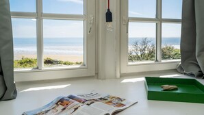 Una habitación con vistas a la playa, una revista sobre la mesa y una bandeja verde con una roca.