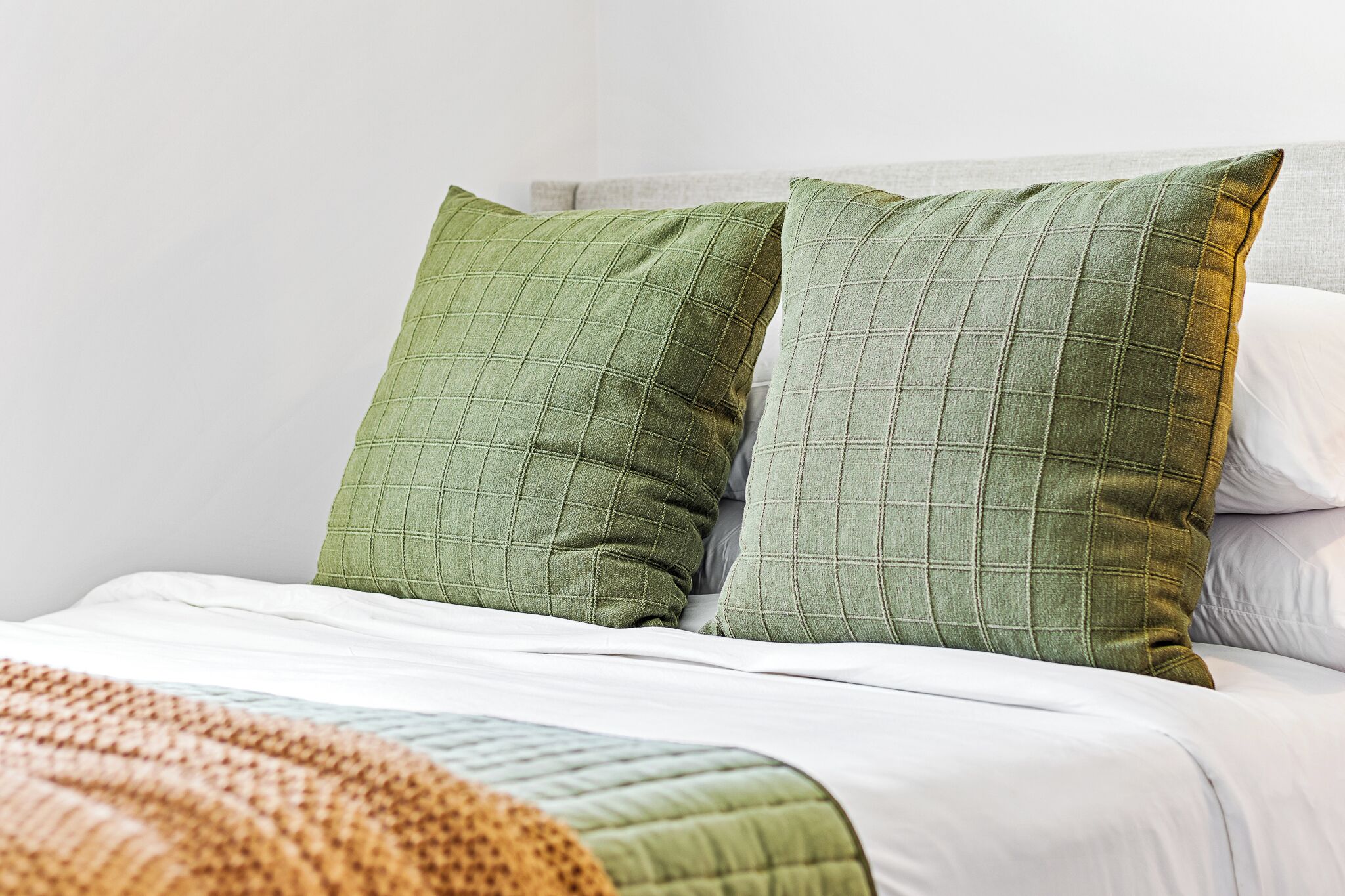 Un lit avec des oreillers verts et une couette blanche.