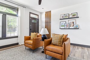 A modern living room with two leather sofas, a black lamp, and framed pictures on the wall.