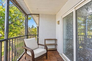 A balcony with a wicker chair, a small table, and a large window with frost.