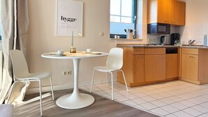 Una cocina moderna con armarios blancos, una mesa redonda de comedor y una lámpara colgante.