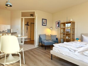 Une chambre d’hôtel comprenant un lit, un canapé, une table à manger avec des chaises, un coin cuisine et une armoire.
