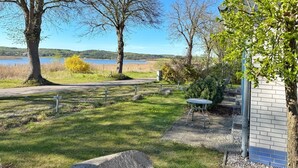 Un parque con un sendero pavimentado, bancos y vistas a un lago y colinas al fondo.