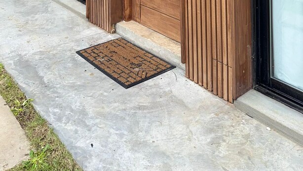 Un edificio moderno con pannelli in legno, ampie porte scorrevoli in vetro e fioriere illuminate esternamente.