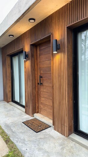 Een modern gebouw met houten lambrisering, grote schuifdeuren van glas en buitenverlichting.