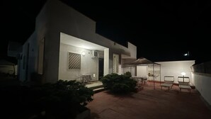 Una casa moderna con un patio que incluye mobiliario exterior y una zona de estar cubierta.