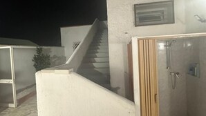 Ein modernes Badezimmer im Freien mit Dusche und einer kleinen Treppe, die zu einer erhöhten Ebene führt.