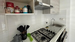 Eine Küche mit weißen Schränken, einem Gasherd und einer Spüle aus Edelstahl.