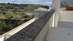 Ein Balkon mit Blick auf eine hügelige Landschaft und das Meer.