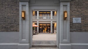 A building entrance with a brick facade, a double balcony, and two lit lanterns. - Blossom Manoir Lujiazui (Shanghai)