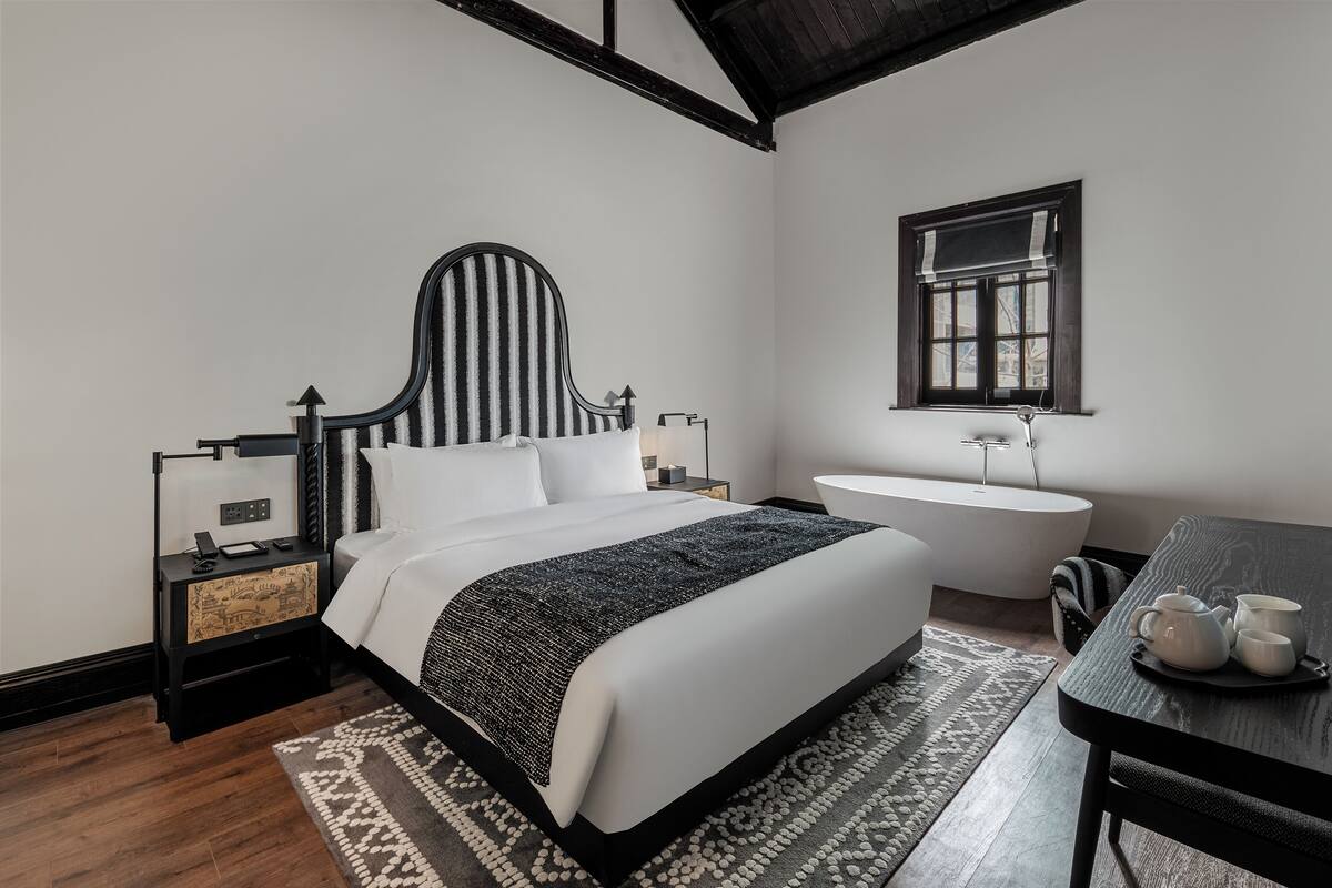 Quarto moderno com cama grande, mesas de cabeceira, pente de vaidade e uma mesa de jantar.