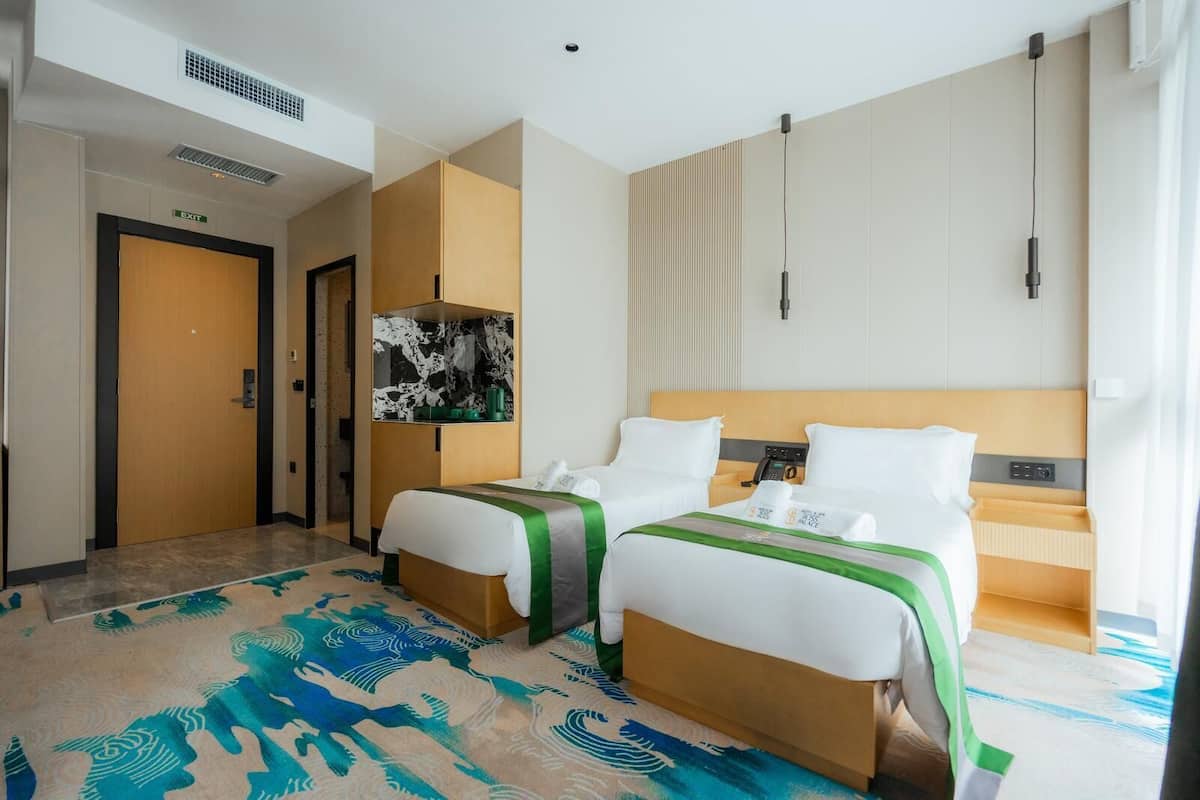 Een hotelkamer met twee bedden, een minibar, een bureau en een badkamer.