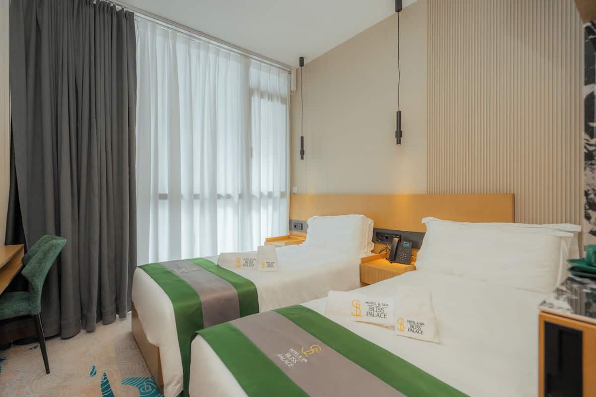 Een hotelkamer met twee bedden, een bureau en een stoel.