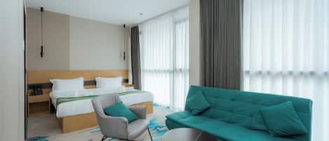 Una habitación de hotel con cama, sofá, sillón y una mesita.