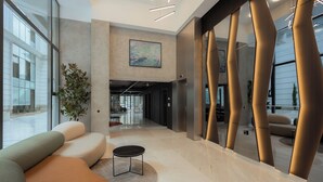 Een moderne lobby met een zithoek, een salontafel en een groot raam met uitzicht.