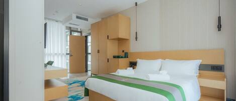 Una habitación de hotel moderna con una cama grande, un escritorio y un armario.
