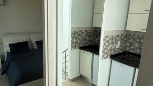 A compact room with a bed, a kitchenette, and a bathroom. - Chic Luxury Duplex in The Heart ofla Marsa - Walk to Beach and Cafés (Marsa)