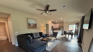Ein modernes Wohnzimmer mit einem grauen Ecksofa, einem Couchtisch und einem Essbereich mit Tisch und Stühlen.