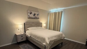 Ein Schlafzimmer mit einem hölzernen Bett, einem Nachttisch mit Lampe, einem Teppich und einem Gemälde an der Wand.