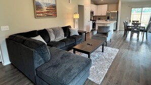 Ein modernes Wohnzimmer mit grauem Sofa, einem Couchtisch und einem Gemälde an der Wand.