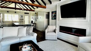 Amplia sala de estar con un sofá blanco, una mesa de centro negra y una chimenea.