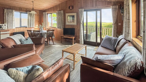 A cozy cabin interior with a dining area, a sofa, and a TV. - 3 bedroom accommodation in Portscatho (Portscatho)