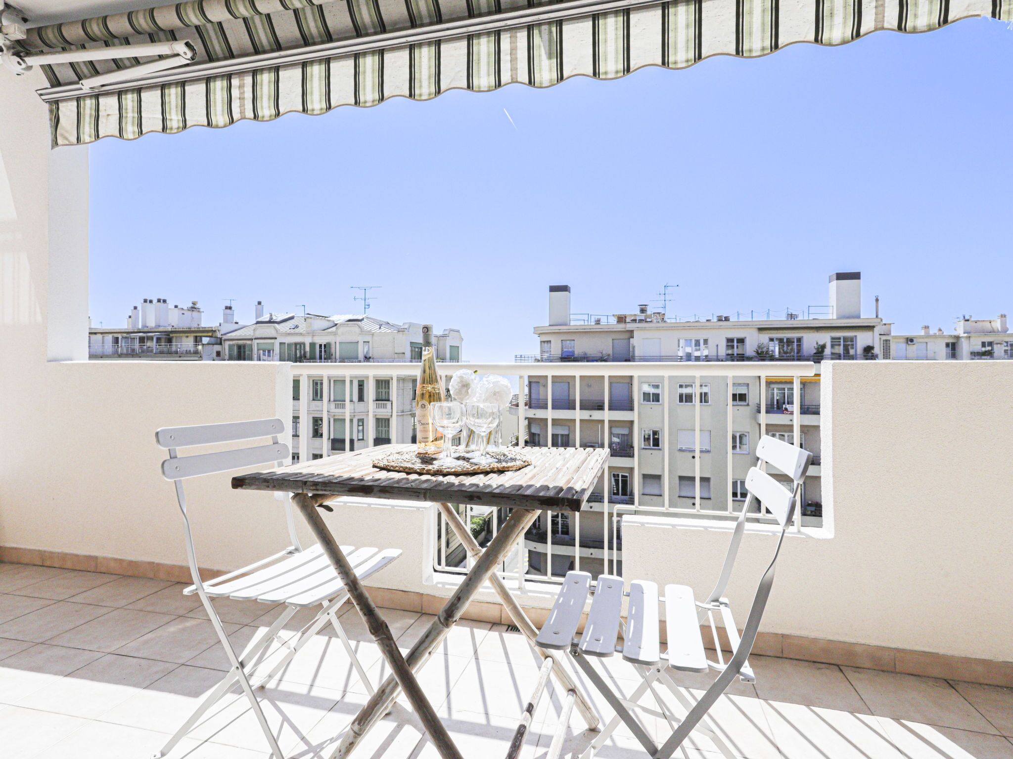 Un balcón con una mesa para dos, una botella de champán y vistas de la ciudad.