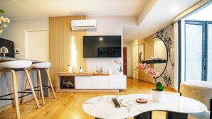 A modern living room with a marble coffee table, wooden flooring, a white entertainment unit, and a flat-screen TV mounted on the wall. - Beautiful and Well Located (Miraflores)