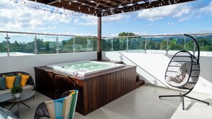 A rooftop terrace with a hot tub, seating area, and hanging chair.