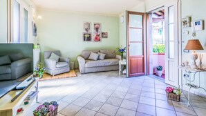 A living room with a grey sofa, a checkered armchair, a small table with a lamp, and a TV on a stand. - Apartment Saida by Interhome (Castiglioncello)