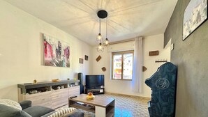 Un soggiorno con divano, tavolino, televisore e un'opera d'arte appesa al muro.
