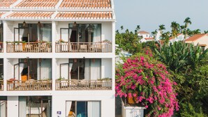A multi-story hotel with balconies, large windows, and a pool area.