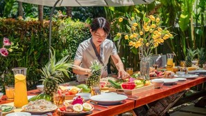 A dining table set outdoors with various fruits and beverages.