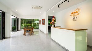 A reception area with a wooden reception desk, a glass partition, and a wall-mounted logo.