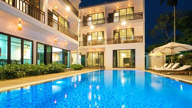 A hotel with a swimming pool, multiple balconies, and outdoor seating.